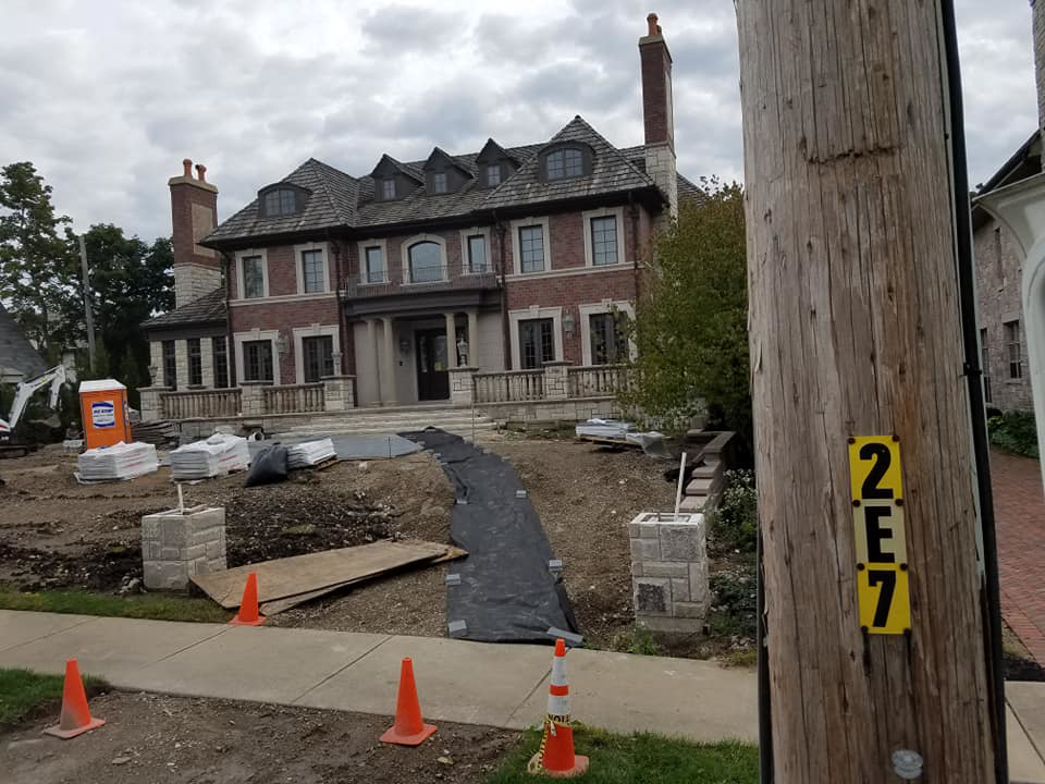 A large residential construction site with materials and disturbed ground, managed by National Kurb Kut in Naperville, IL.
