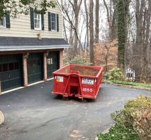 A red Geppert Recycling dumpster placed on a residential driveway for junk removal in Philadelphia, PA.
