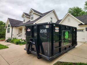 A black KC Brothers Disposal dumpster parked in a residential driveway for waste removal in Kansas City, MO.