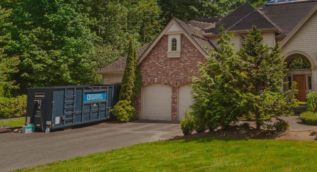 A blue Discount Dumpster roll-off container placed in the driveway of a large residential home in Naples, FL, for junk removal.