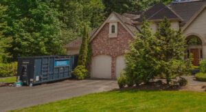 A blue Discount Dumpster roll-off container placed in the driveway of a large residential home in Naples, FL, for junk removal.
