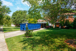 A large blue roll-off dumpster placed in a residential driveway for junk removal services by Dumpster 360 in Clarksville, TN.