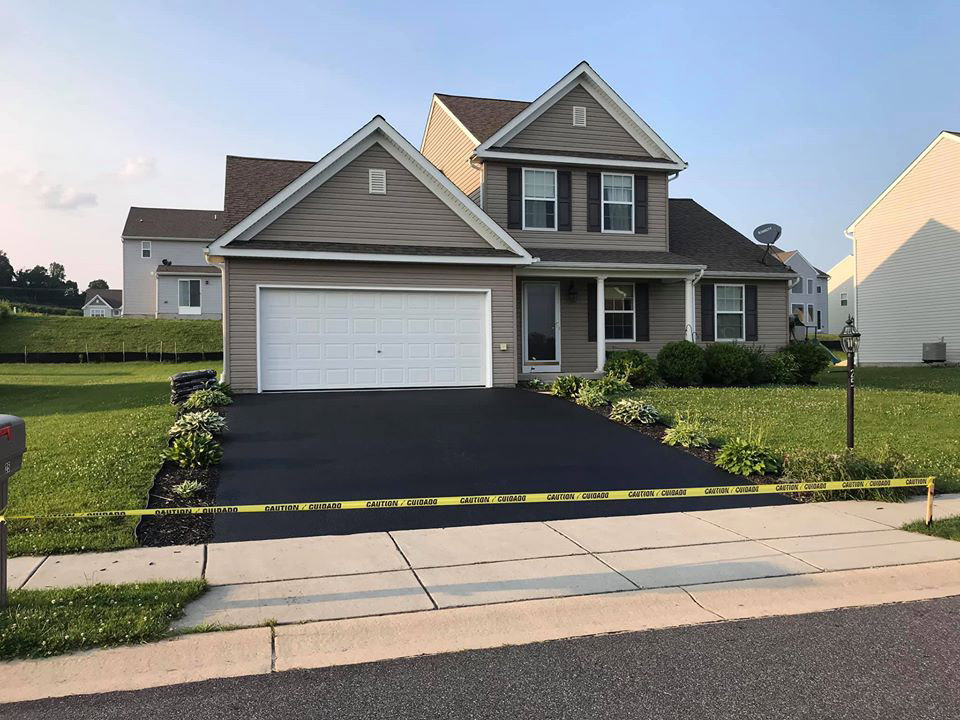 A newly paved residential driveway with caution tape, completed by Angeles Contractors LLC in New Oxford, PA.