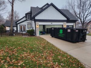 A black KC Brothers Disposal dumpster delivered to a residential driveway for junk removal in Kansas City, MO.