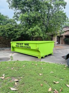 A bright green dumpster delivered to a residential property for junk removal by Tristate Dumpsters LLC in Greenville, MS.