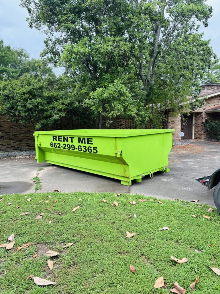 A bright green dumpster delivered to a residential property for junk removal by Tristate Dumpsters LLC in Greenville, MS.
