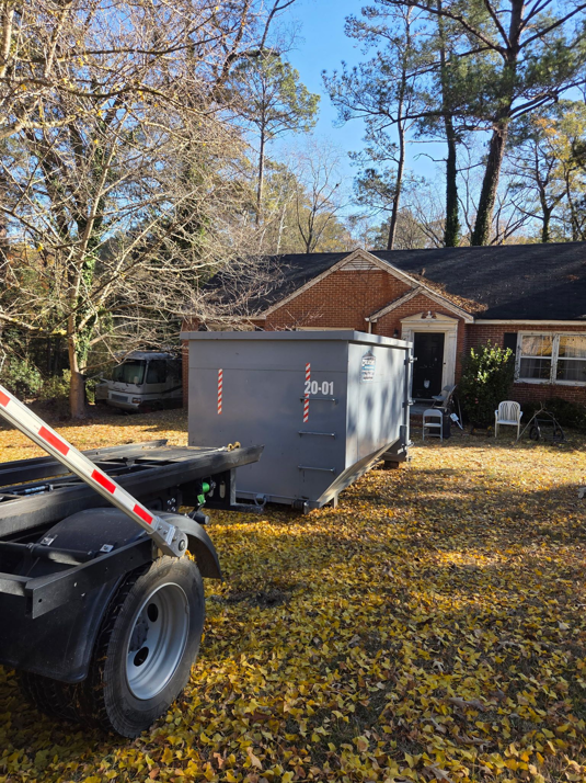 A Creative Disposal Services truck placing a dumpster for residential junk removal at a home in Macon, GA.