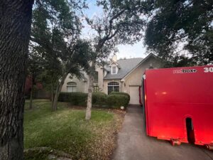 A redbox+ dumpster placed in front of a residential house for junk removal by redbox+ Dumpsters of Greater Austin in Austin, TX