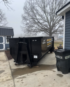 A black dumpster from Disposal Pro Haul Away Services placed on a residential driveway for junk removal in Charlotte, NC.