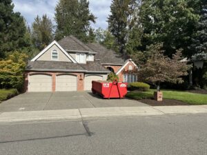 A red dumpster from Cascade Container and Recycling with a 'Rent Me' sign in a residential driveway in Seattle, WA.