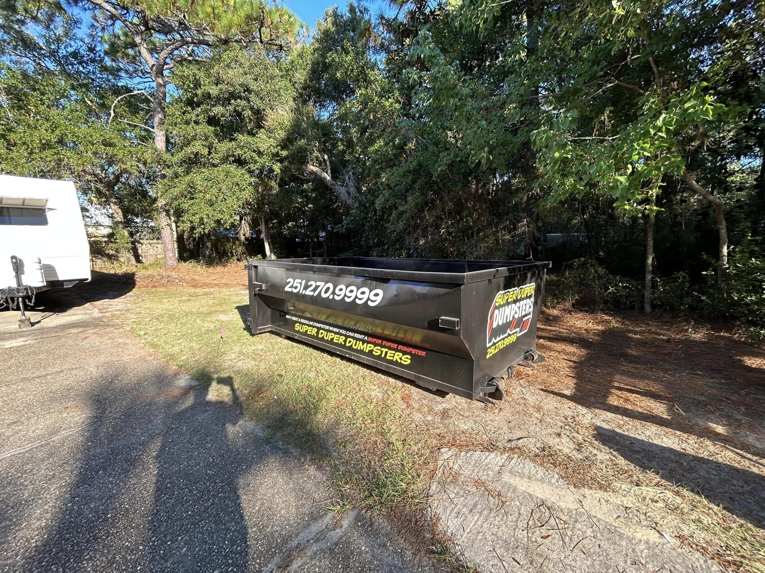 A Super Duper Dumpsters roll-off container placed in a residential yard for junk removal in Mobile, AL.