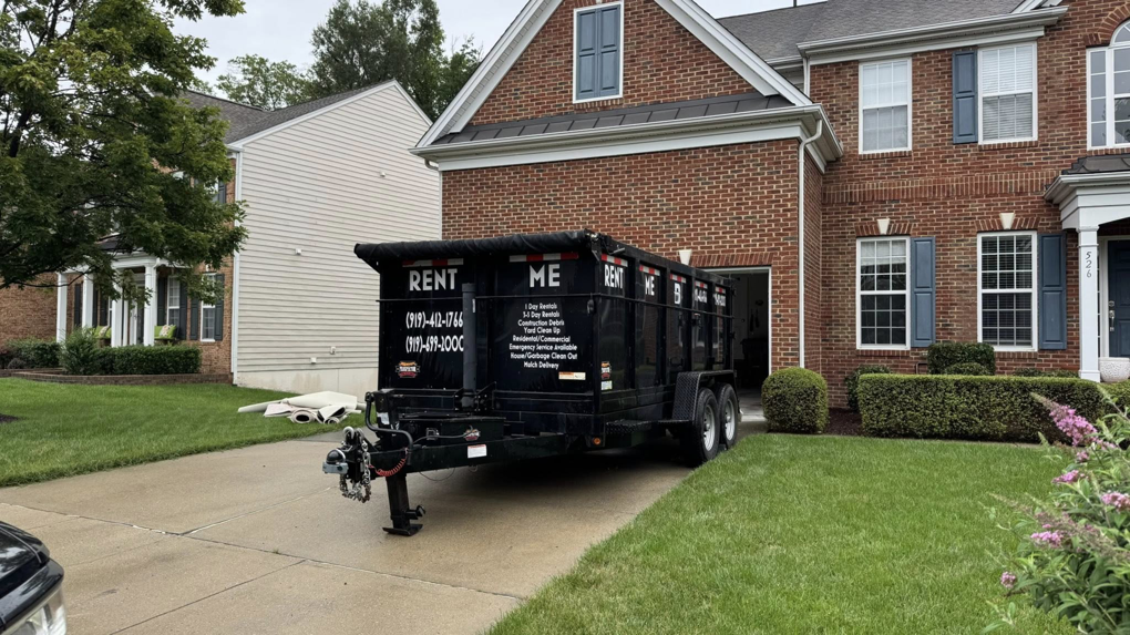 A black dump trailer from The Dump Bros LLC parked in a residential driveway for junk removal in Raleigh, NC.