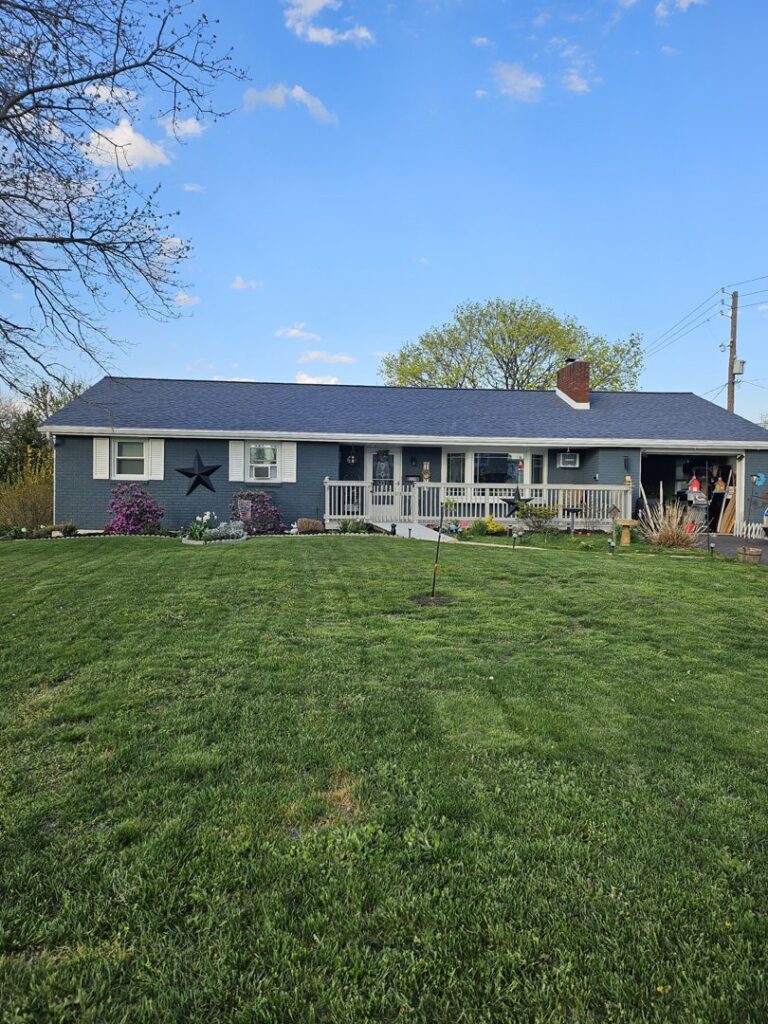 A residential home showcasing a recently completed exterior renovation with new dark blue roof and light blue siding by Glick's Exteriors in Philadelphia, PA.