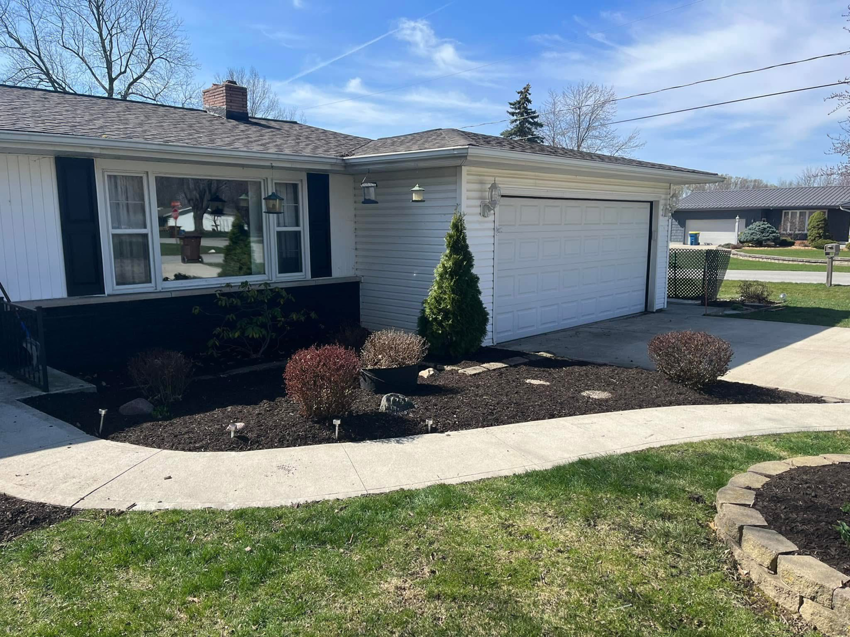 A residential front yard featuring fresh mulch and neatly trimmed bushes by E&K Property Preservation in Lake, MI.