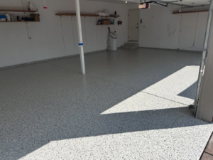 A clean residential garage featuring a new light grey speckled epoxy floor coating by 812 Concrete Coatings in Evansville, IN.
