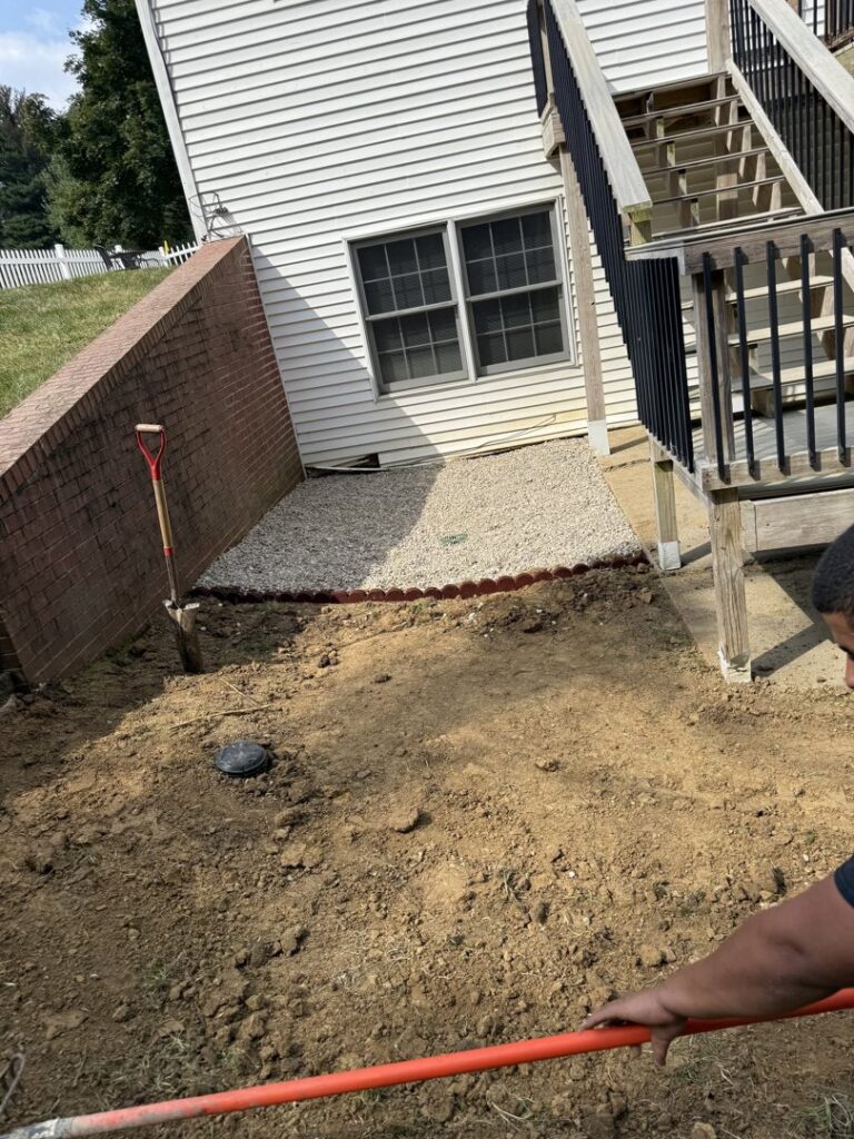Groundwork being performed next to a residential house with a shovel, indicating a small excavation project by Lankford Dirt Works LLC in Indianapolis, IN.