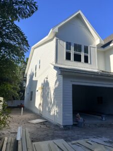 Residential home construction showing white siding installation and an open garage by M&J Florida Enterprise Llc in Orlando, FL.