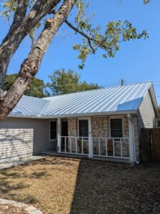 A residential house featuring a new metal roof and stone and siding exterior by Austin Roofing and Construction in Austin, TX.