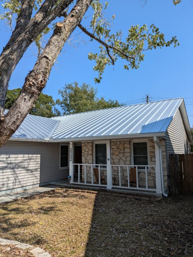 A residential house featuring a new metal roof and stone and siding exterior by Austin Roofing and Construction in Austin, TX.