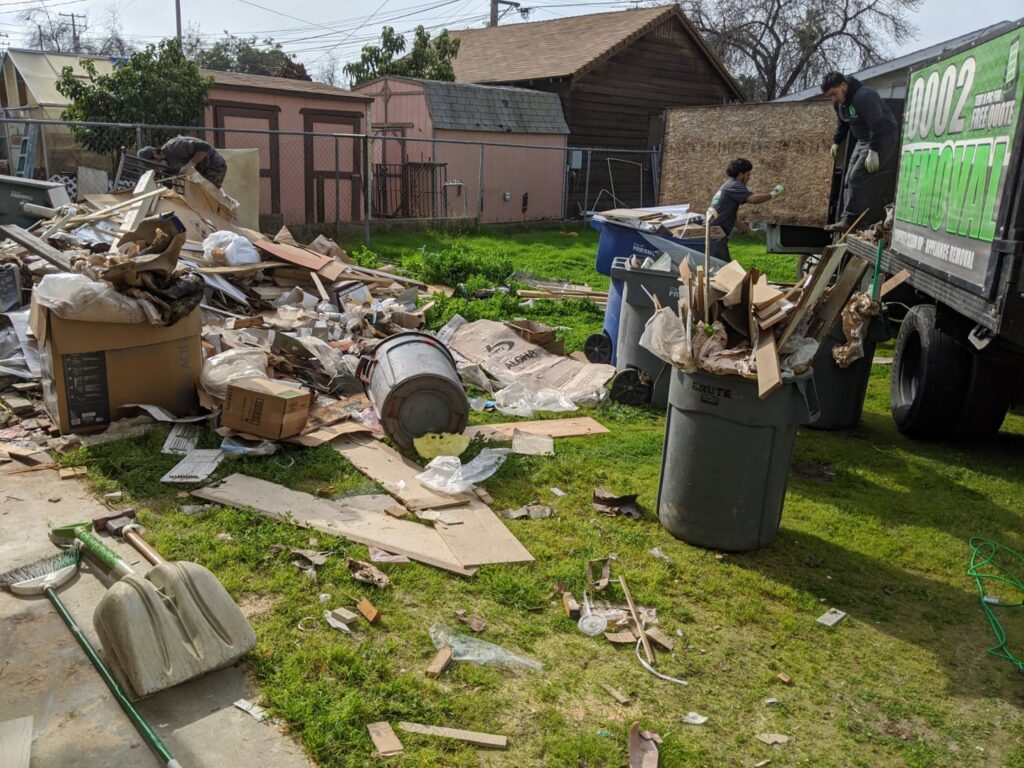 A truck loaded with appliances and household junk on a residential street for Haul-R-Us Junk Removal LLC in Fresno, CA.