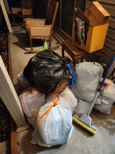 A pile of trash bags and miscellaneous junk on a residential porch, ready for pickup by MOAT's Junk Removal LLC in Jonesboro, AR.