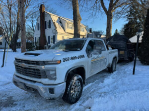 Rubbish Doctor truck and trailer parked in a snowy residential driveway for junk pickup in Portland, ME.