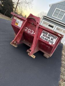 A red Geppert Recycling dumpster placed on a residential driveway for junk removal services in Philadelphia, PA.
