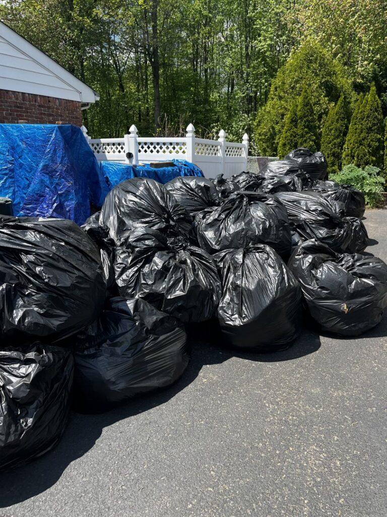 A large pile of black trash bags ready for residential junk removal by Green Street Services in Woodbridge Township, NJ.