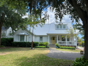 A charming white house with a newly installed white metal roof, showcasing a completed project by Hastings Roofing Service Inc. in Orlando, FL.