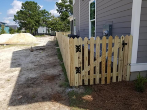 A new wooden picket fence and gate installed along the side of a residential property by Frontline Fencing LLC in Summerville, SC.