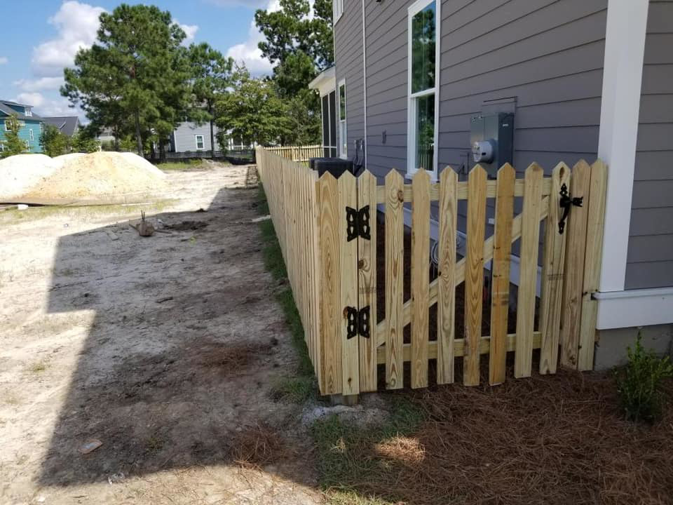 A new wooden picket fence and gate installed along the side of a residential property by Frontline Fencing LLC in Summerville, SC.