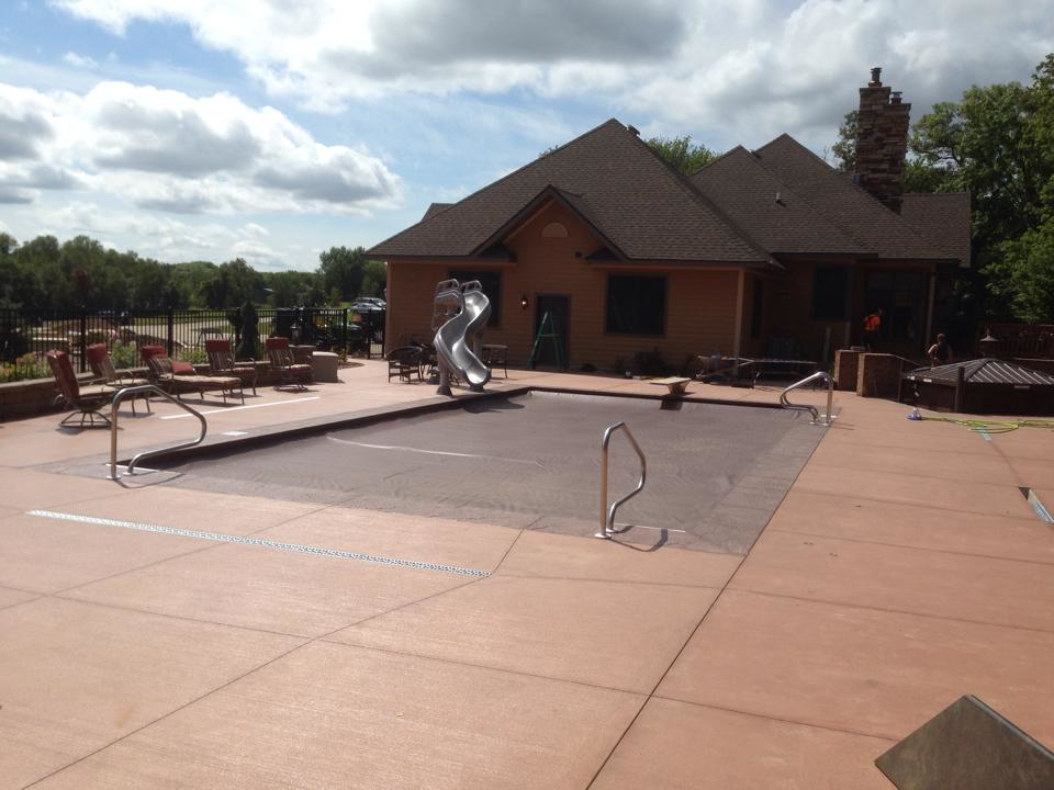 A spacious residential pool area with a slide and a view of the main house, completed by Ankeny Builders L.L.C. in Eau Claire, WI.