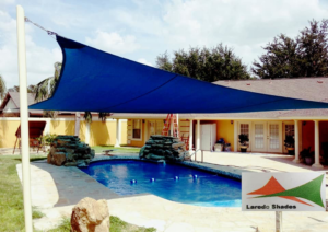A blue shade sail installed over a residential swimming pool by Laredo Shades, a general contractor in Laredo, TX.
