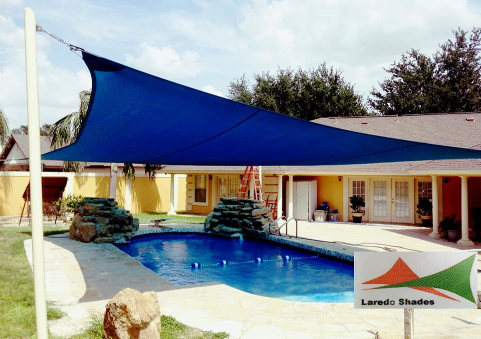 A blue shade sail installed over a residential swimming pool by Laredo Shades, a general contractor in Laredo, TX.