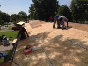 Multiple workers installing new plywood and underlayment on a residential roof by Gwen Co in St. Louis, MO.