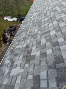 A residential roof replacement project showing new shingles and cars below, by New American General Construction INC in Richmond, VA.
