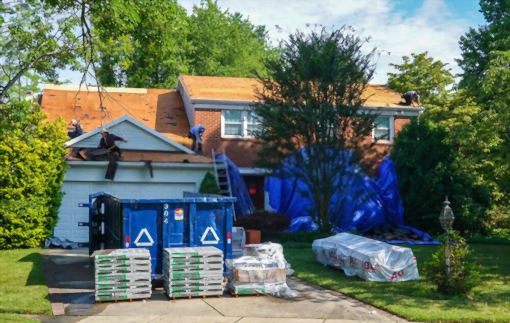A blue dumpster in the driveway of a residential home undergoing a roofing project, provided by Dumpster 360 in Clarksville, TN.