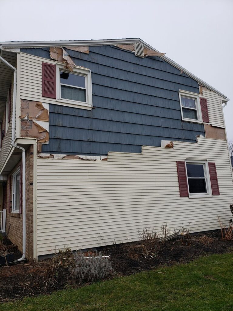 Residential house with severe siding damage requiring repair by Naples Roofing & Sheet Metal LLC in Buffalo, NY