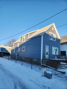 A residential house with newly installed blue siding and a new roof, completed by J and R Contracting in Buffalo, NY.