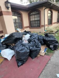A pile of black trash bags and cardboard boxes outside a home for junk removal by The Removal Squad LLC in Orlando, FL.