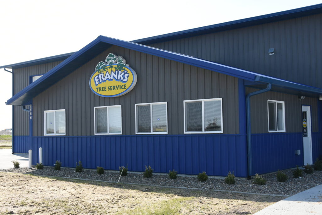 A Frank's Tree Service worker in a bucket truck pruning a tree in a residential area of Davenport, IA.