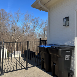 Two Current Waste Solutions residential waste bins, one with a blue lid, on a patio in Louisville, KY.
