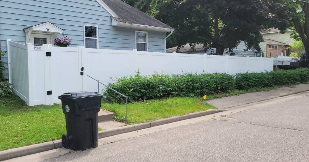 A residential white privacy fence with a gate, expertly installed by Cyclone Fence in Somerset, WI.