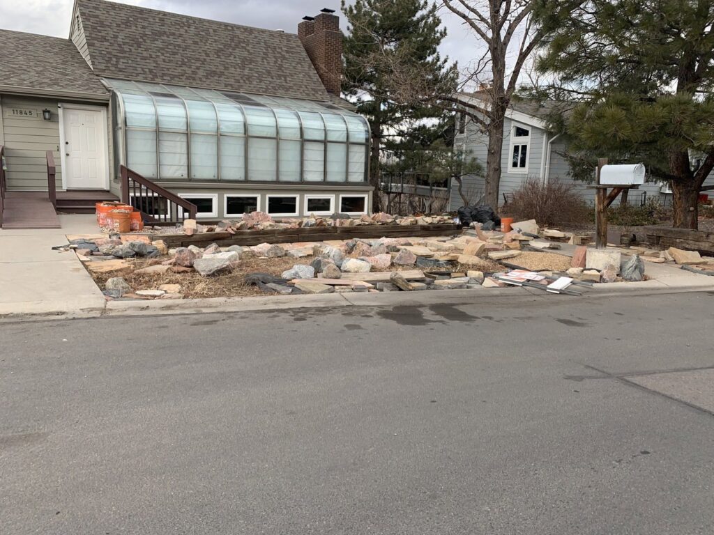 A residential yard with piles of rocks, wood, and debris ready for general junk removal by Discount Dumpster in Naples, FL.