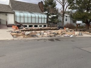 A residential yard with piles of rocks, wood, and debris ready for general junk removal by Discount Dumpster in Naples, FL.