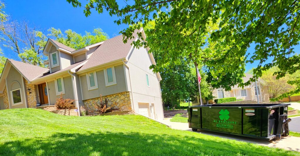 A black KC Brothers Disposal dumpster placed in a residential yard for junk removal services in Kansas City, MO.