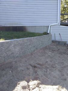 Exterior view of a house with a retaining wall under construction by Honey Bee's Handyman Services in Hastings, NE.