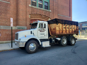 A Rhode Island Disposal dump truck with a large roll-off container parked on a street in Providence, RI.