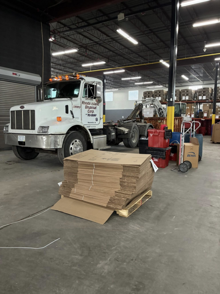 A Rhode Island Disposal roll-off truck parked inside a spacious garage, ready for service in Providence, RI.