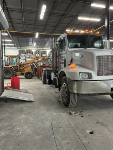 Rhode Island Disposal truck and a backhoe next to a roll-off dumpster in a facility in Providence, RI.